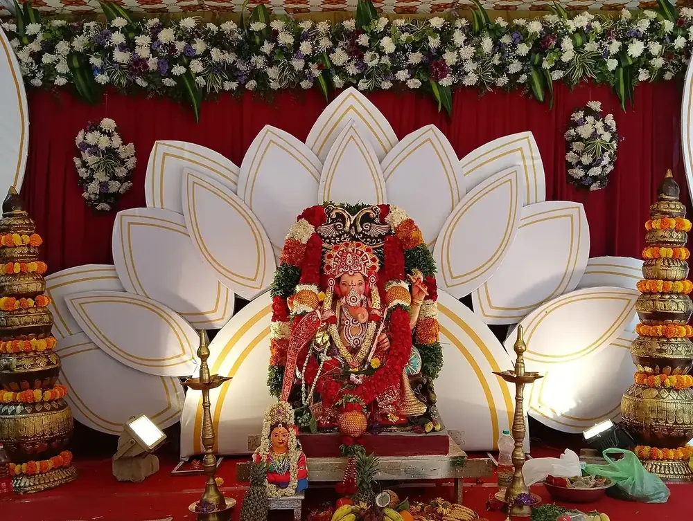 Wedding stage with a lotus backdrop, the deity at the centre and brass lamps