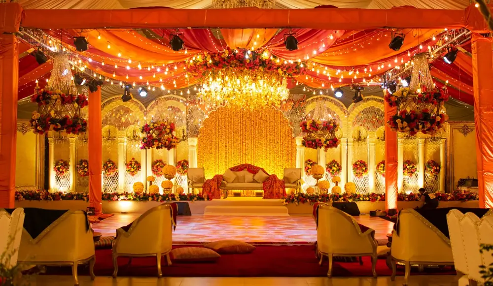A grand wedding stage in gold and orange under chandeliers
